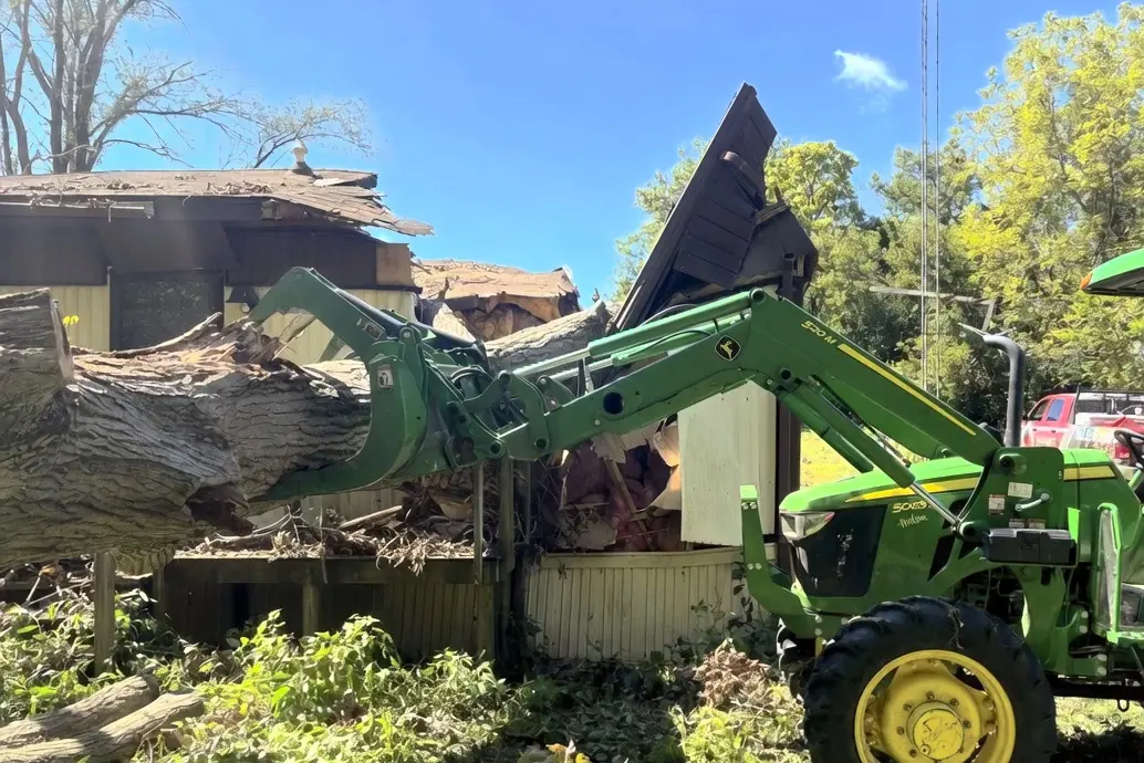 Large tree being removed from a damaged structure with equipment